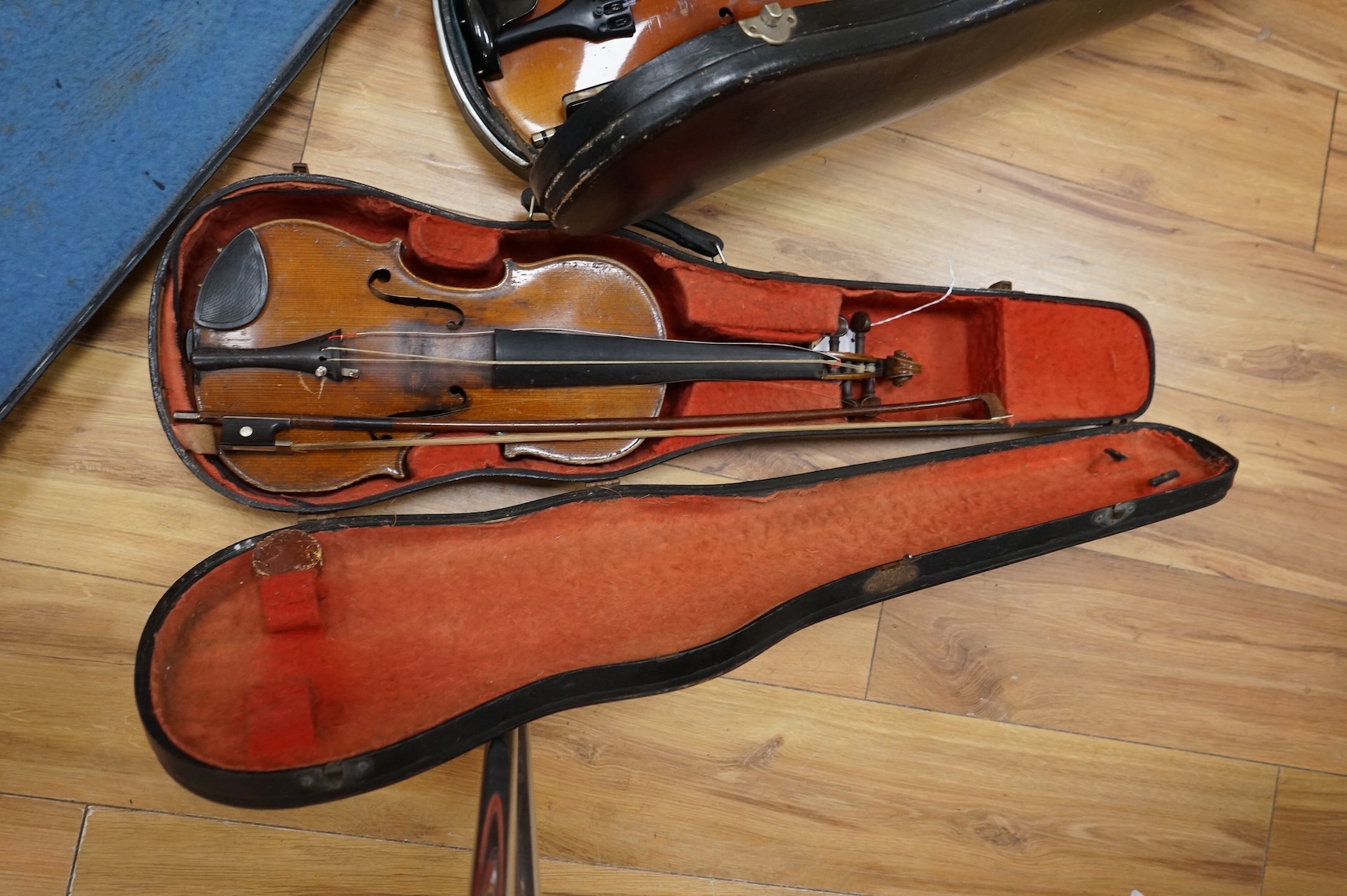 Five cased 20th century violins, including; a German violin, two Czech violins, a three-quarter size violin with a label for Bienfait, and a Romanian quarter size violin, all in cases or the remains of cases.